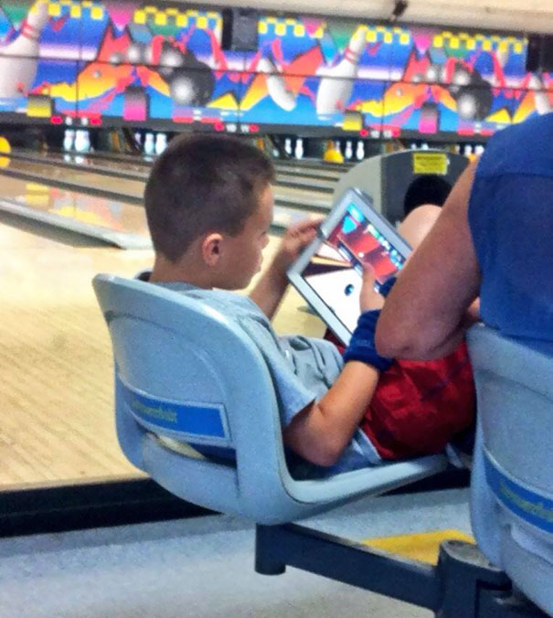 This Kid Is Playing A Bowling Game At A Bowling Alley