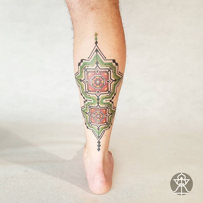 Amazonian tribal art tattoo on leg with geometric patterns and earthy colors.