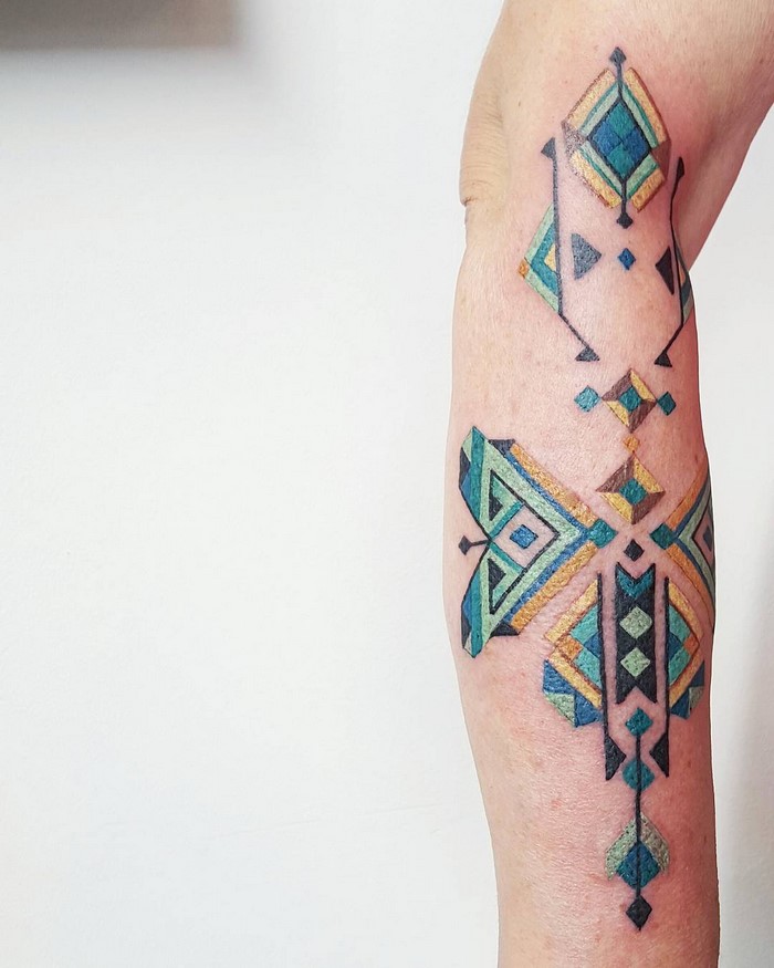 Amazonian tribal tattoo by Brazilian artist Brian Gomes, featuring geometric designs in blue and yellow tones.