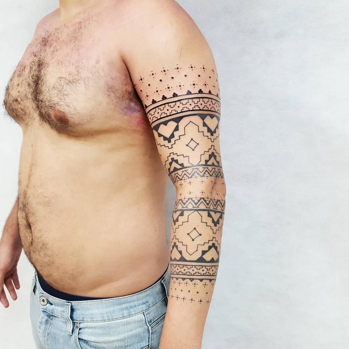 Man with an arm tattoo featuring Amazonian tribal art patterns by Brazilian artist.
