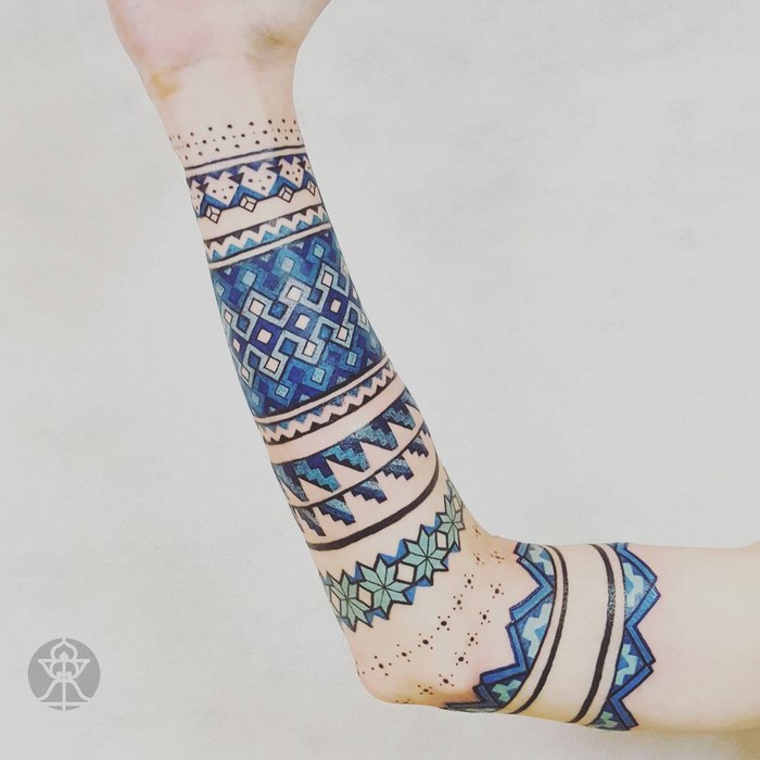 Arm showcasing Amazonian tribal art tattoo designs by Brazilian artist, featuring geometric patterns in blue tones.