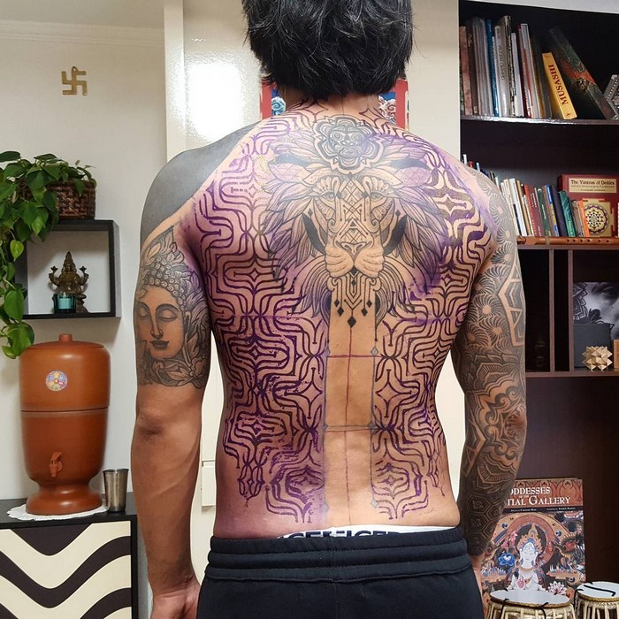 Man with intricate Amazonian tribal tattoo art by Brazilian artist on his back, showcasing detailed patterns.
