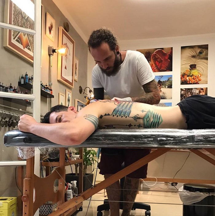 A man getting an Amazonian tribal art tattoo by Brazilian artist in a studio.