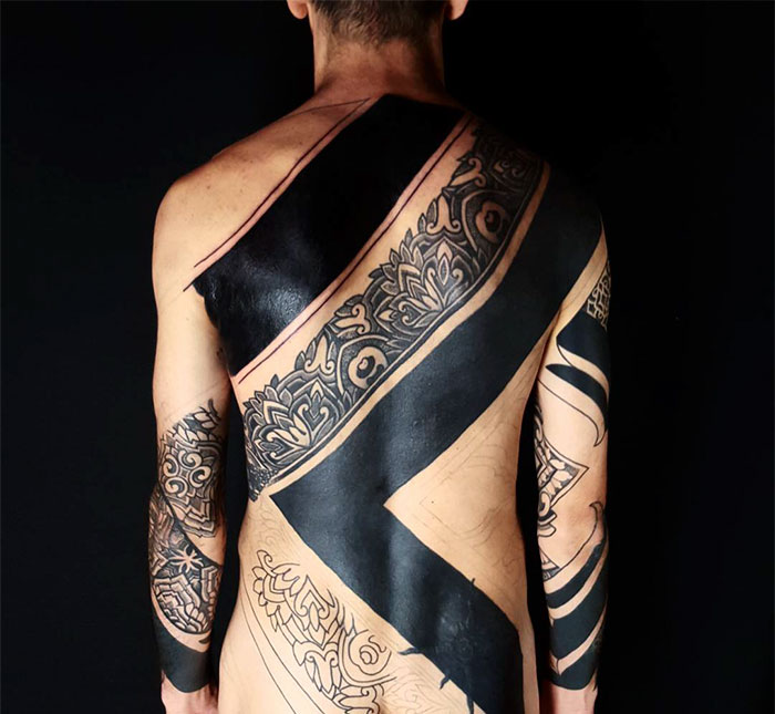 Back view of a person with Amazonian tribal art tattoos in black and grey, created by Brazilian artist Brian Gomes.