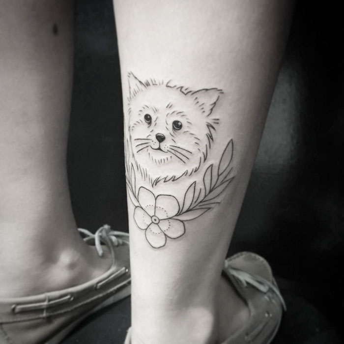 Dog tattoo design on leg featuring a dog's face with floral elements.