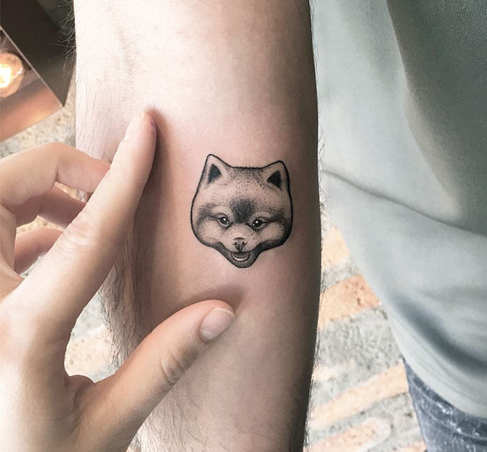 Dog tattoo on arm, featuring a detailed dog face design.