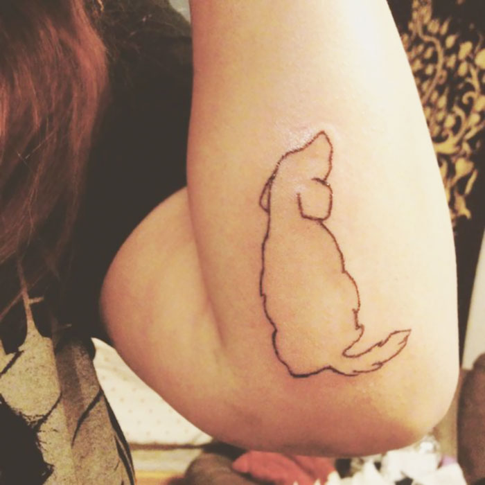 Outline of a dog tattoo on an arm, showcasing a simple and minimalistic design.