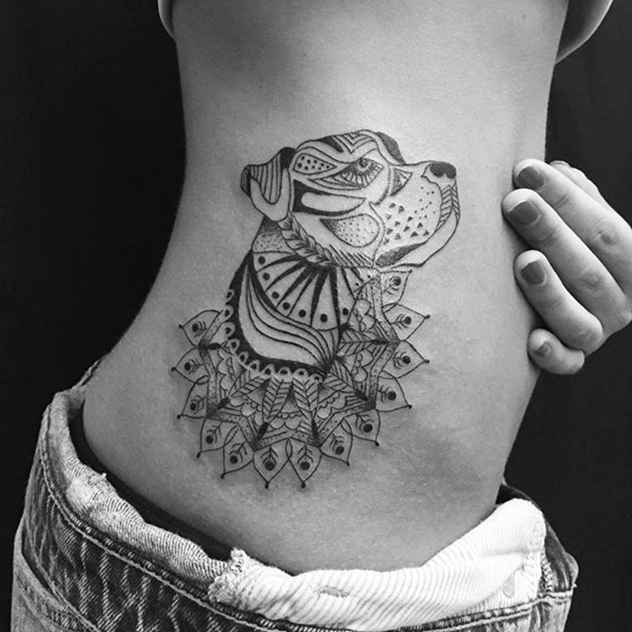 Ornate dog tattoo design on person's side, showcasing intricate patterns and artistic detail.