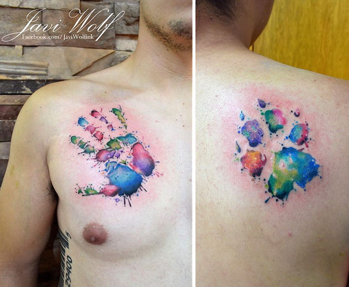 Colorful dog paw tattoo on shoulder and handprint tattoo on chest, vibrant watercolors blending in artistic design.
