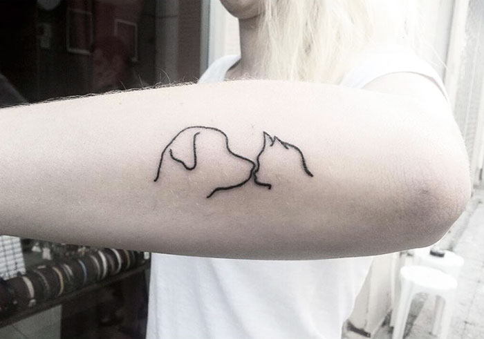 Minimalist dog tattoo design on a person's forearm, featuring a simple outline.
