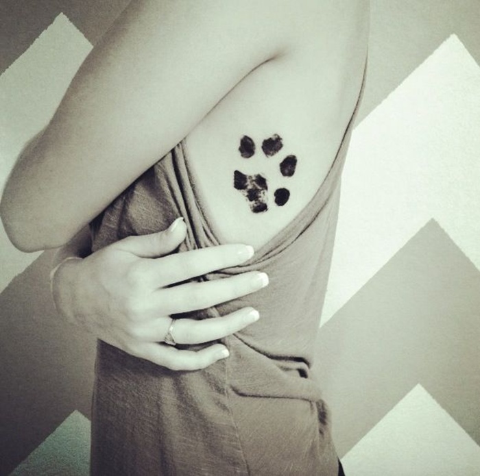Woman with a dog paw tattoo on her side, symbolizing love for pets and canine loyalty.