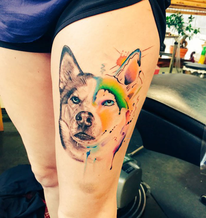 Colorful dog tattoo on thigh featuring vibrant watercolor design.