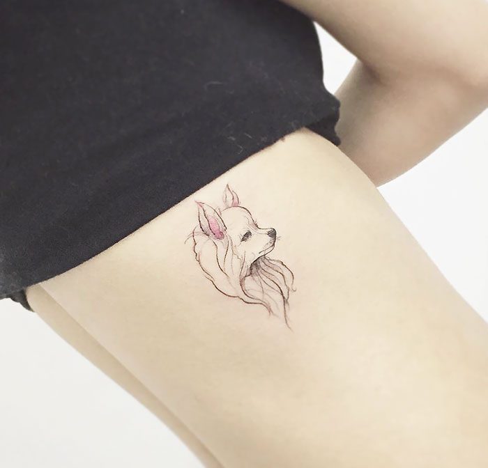 Minimalist dog tattoo on a person's thigh, featuring a detailed sketch of a small dog's face.