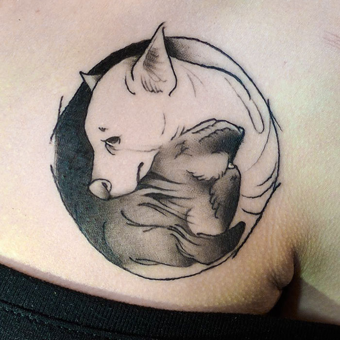 Yin-yang dog tattoo with two resting dogs intertwined, symbolizing balance and harmony.