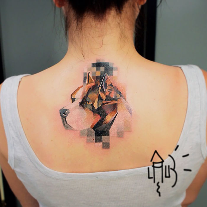 Creative geometric dog tattoo on woman's back, featuring abstract design with vibrant colors and pixelated effect.