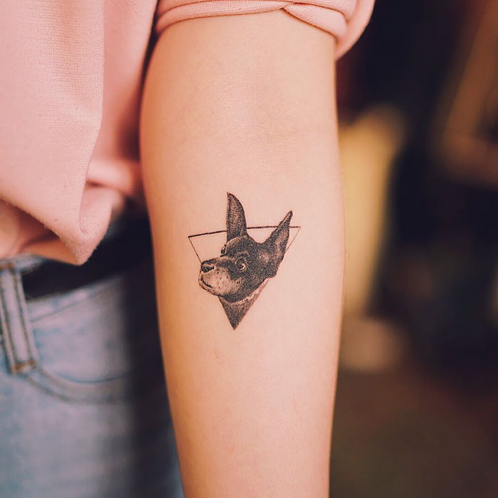 Dog tattoo on arm featuring a geometric design with a dog's face.