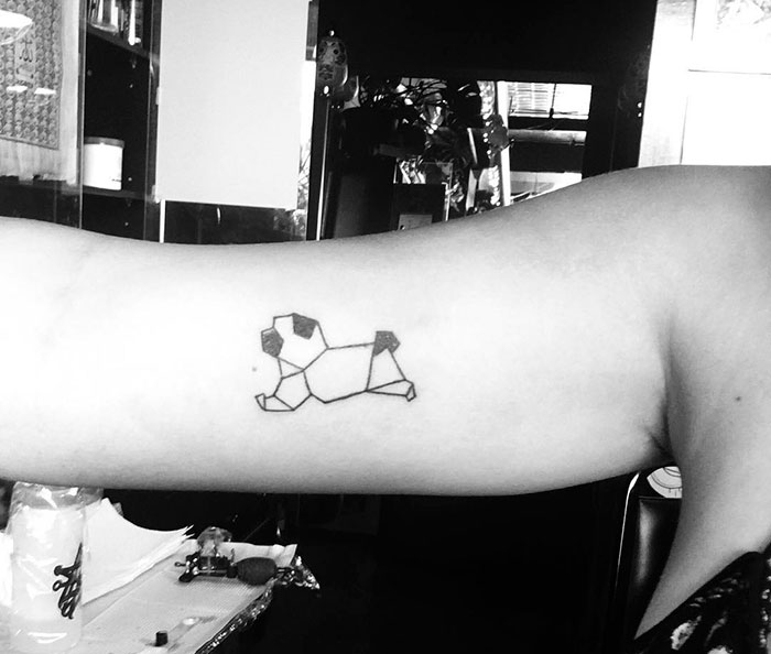 Geometric dog tattoo on inner arm, illustrating unique dog tattoo idea.