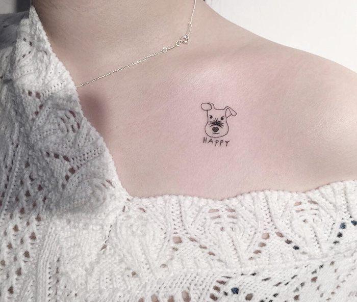Minimalist dog tattoo on shoulder with the word "Happy" under it.