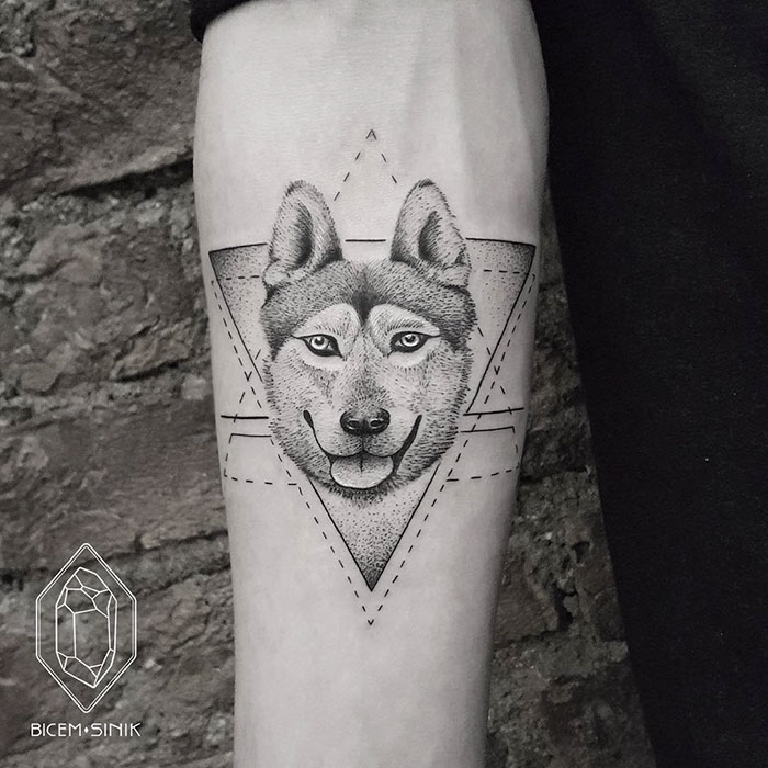 Geometric dog tattoo design on forearm featuring intricate details and lines.
