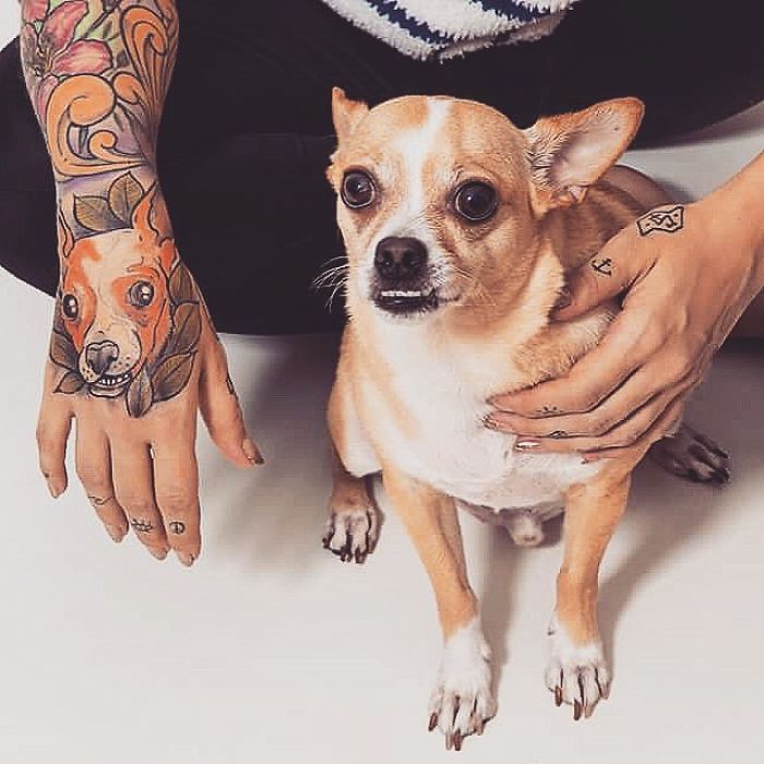 Person with colorful dog tattoo on arm, holding a small brown and white dog, showcasing tattoo ideas.