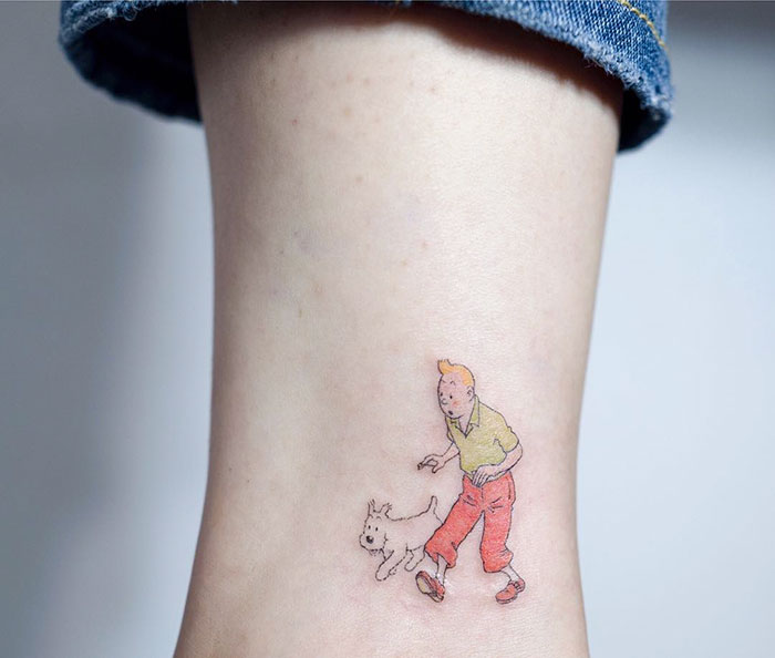 Minimalist tattoo of a person with a dog on an ankle, showcasing unique dog tattoo ideas.