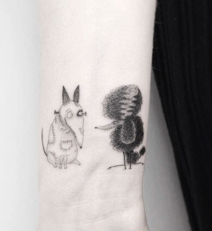 Minimalist dog tattoo featuring whimsical, cartoon-style dogs on an arm.