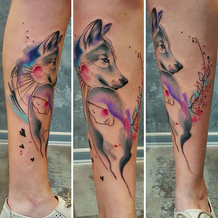 Watercolor style dog tattoo on a leg, featuring vibrant colors and abstract design.