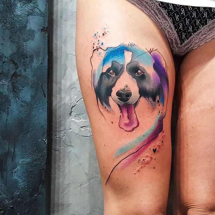 Vibrant dog tattoo on thigh with abstract watercolor design, showcasing one of the best dog tattoo ideas.