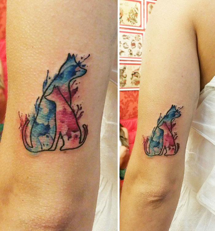 Watercolor dog tattoo design on arm showcasing vibrant blues and pinks.