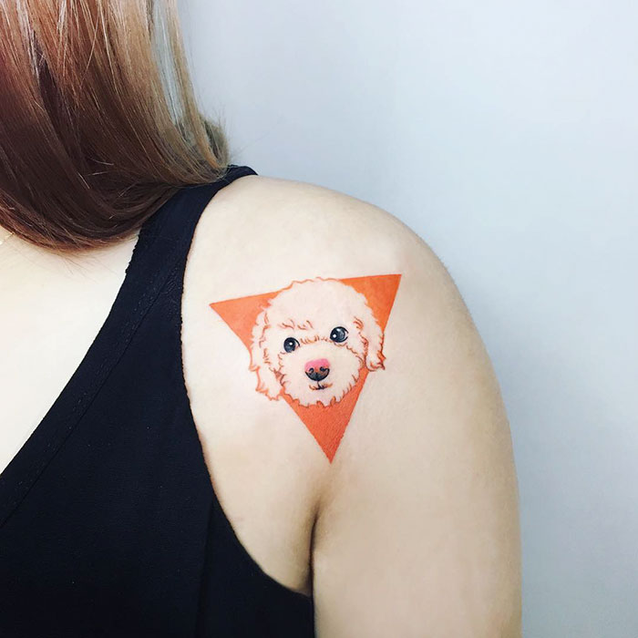 Shoulder tattoo of a dog face in a triangular design.