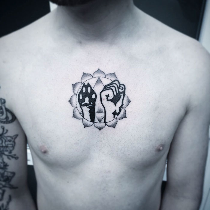 Chest tattoo featuring dog paw and fist, surrounded by a geometric design, highlighting unique dog tattoo ideas.