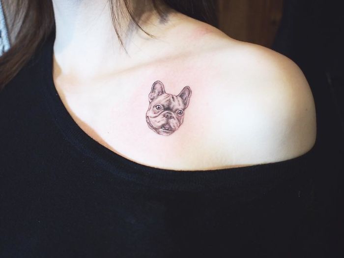 Small dog tattoo on woman's shoulder, showcasing pet portrait artistry.