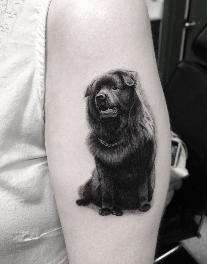Dog tattoo on arm, featuring a realistic black dog design.