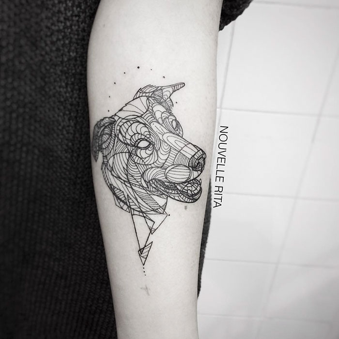 Geometric dog tattoo design on forearm showcasing intricate line work in black ink.