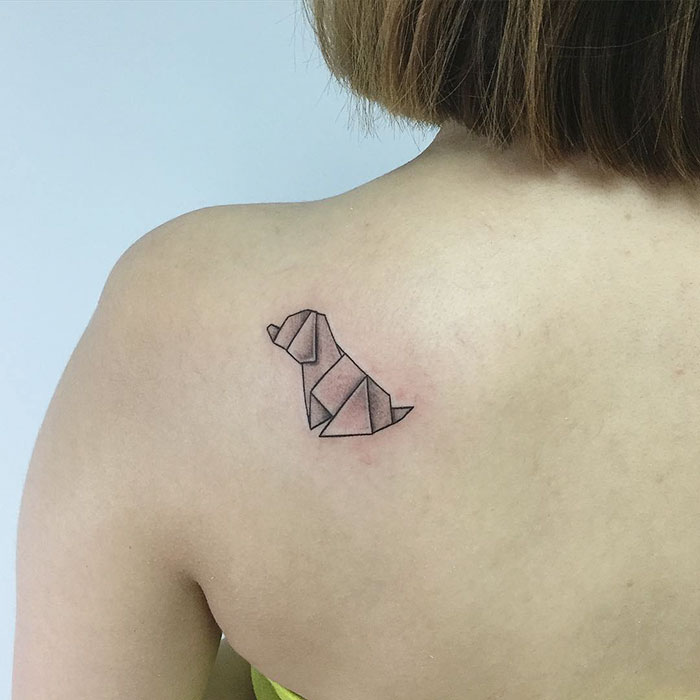 Minimalist geometric dog tattoo on a person's upper back.