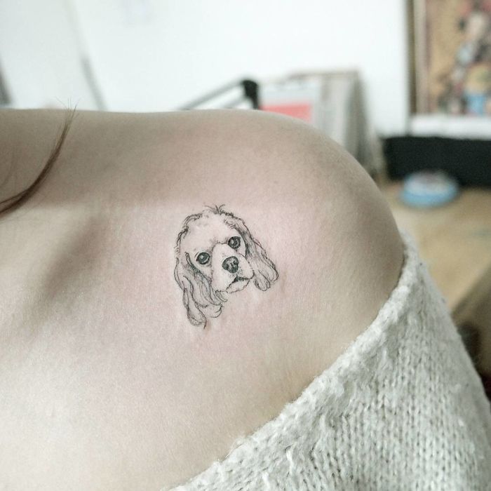 Dog tattoo on shoulder featuring a delicate dog portrait design.