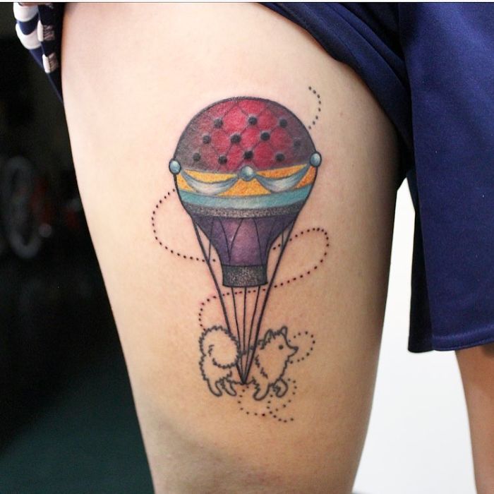 Dog tattoo with a hot air balloon design on a person's thigh.