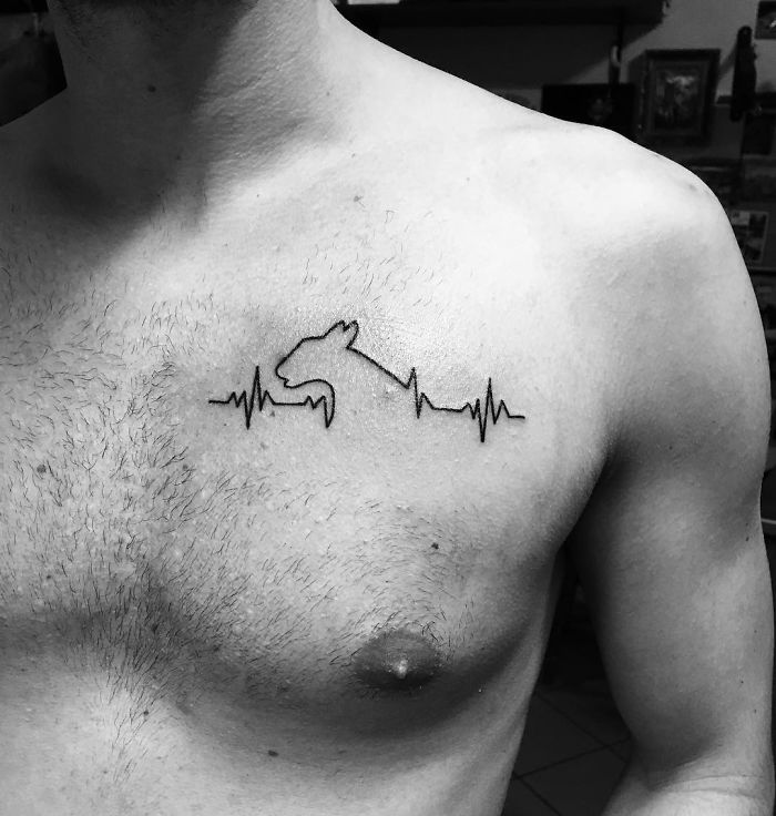 Minimalist dog tattoo with heartbeat design on a man's chest.