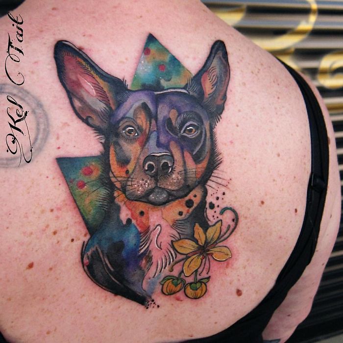 Colorful abstract dog tattoo on shoulder with geometric shapes and flowers.