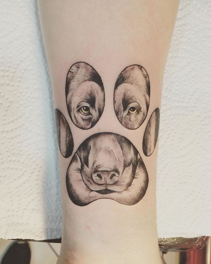 Dog tattoo design on forearm, featuring a dog's face and paw print artfully combined.