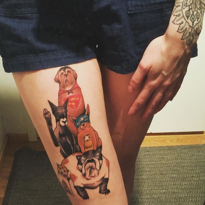 Tattoo of superhero-themed dogs on a person's thigh, showcasing creative dog tattoo ideas.
