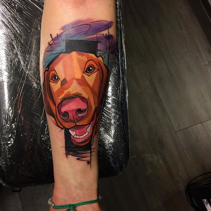 Colorful geometric dog tattoo design on forearm.