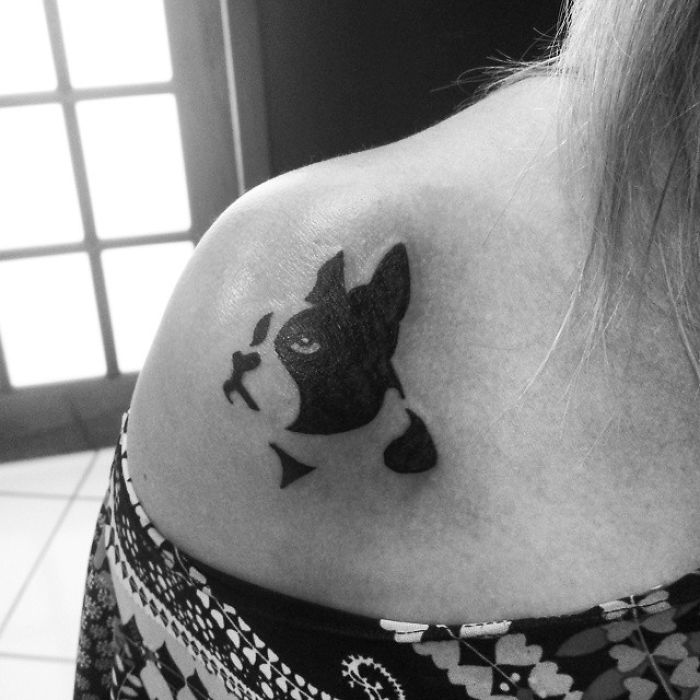Tattoo of a stylized dog face on a shoulder, showcasing one of the best dog tattoo ideas.