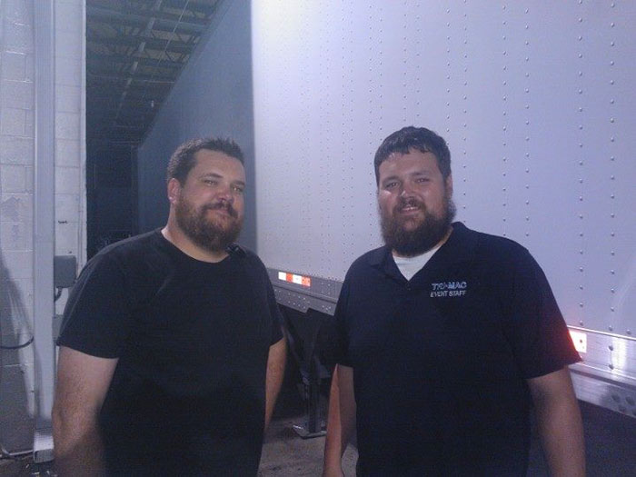 Two doppelgangers standing next to a truck 
