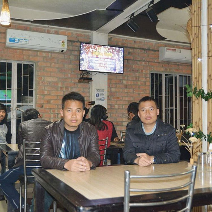 Two doppelgangers sitting near a table in cafe 
