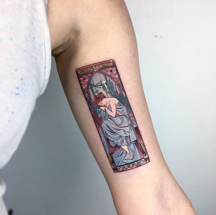 Classical art-inspired tattoo on a person's arm, featuring a detailed figure in an ornate frame.