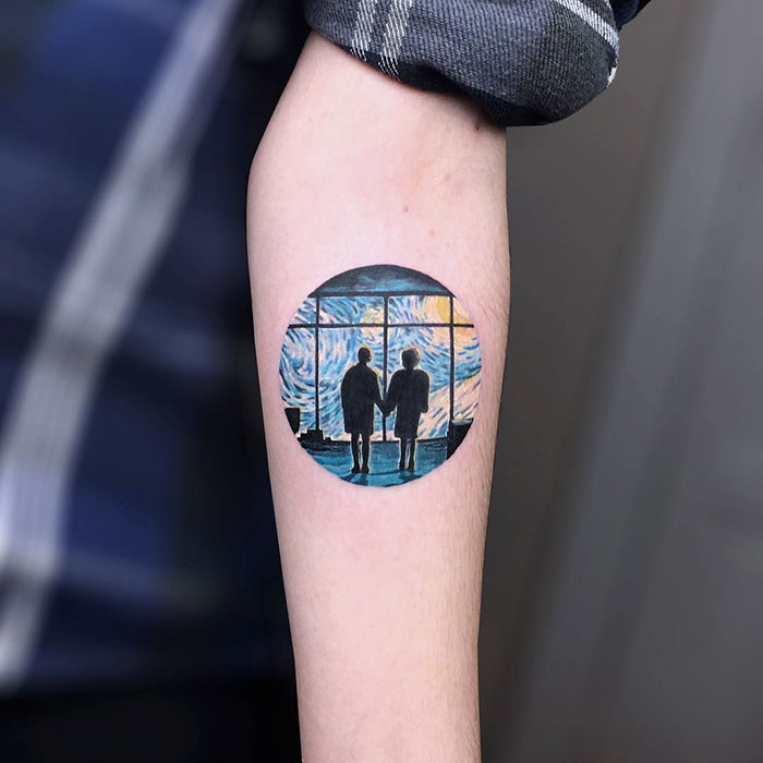 A tattoo on an arm depicting two figures silhouetted against a starry night, inspired by classical art.