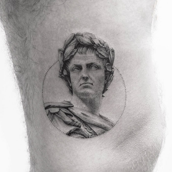 Classical art-inspired tattoo of a Roman statue head in black ink.