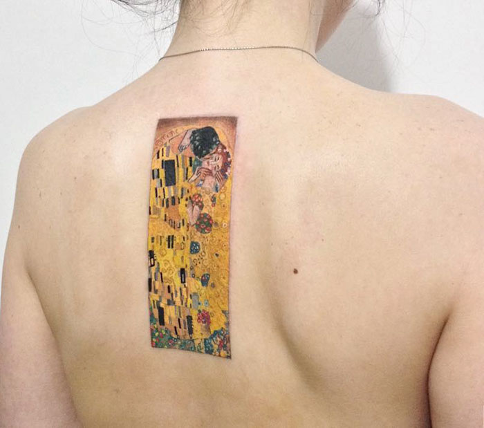 Classical art-inspired tattoo of Klimt's "The Kiss" on a person's back.