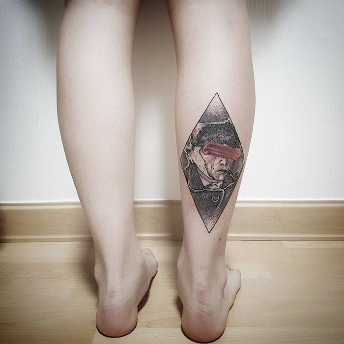 Classical art-inspired tattoo on a person's calf, featuring a portrait with red accent.